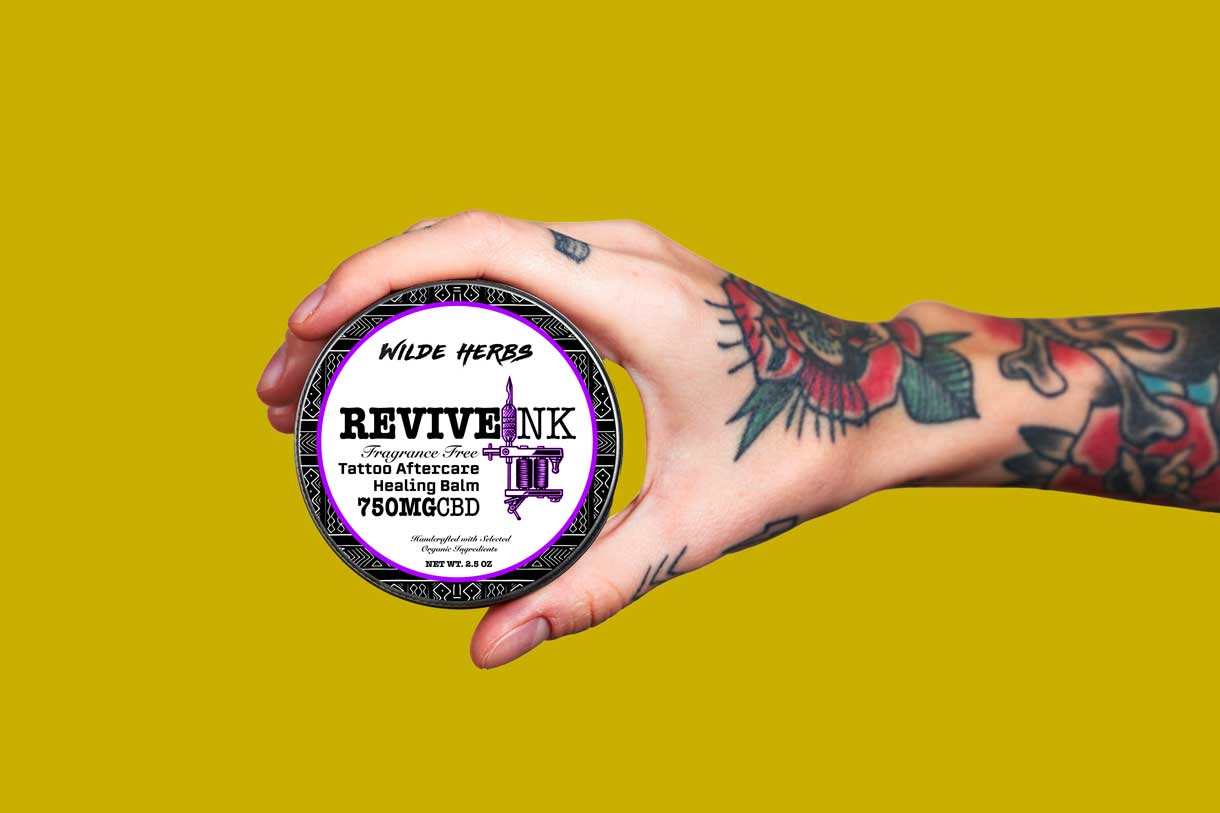 Hand holding Revive ink CBD topical cream for tattoos